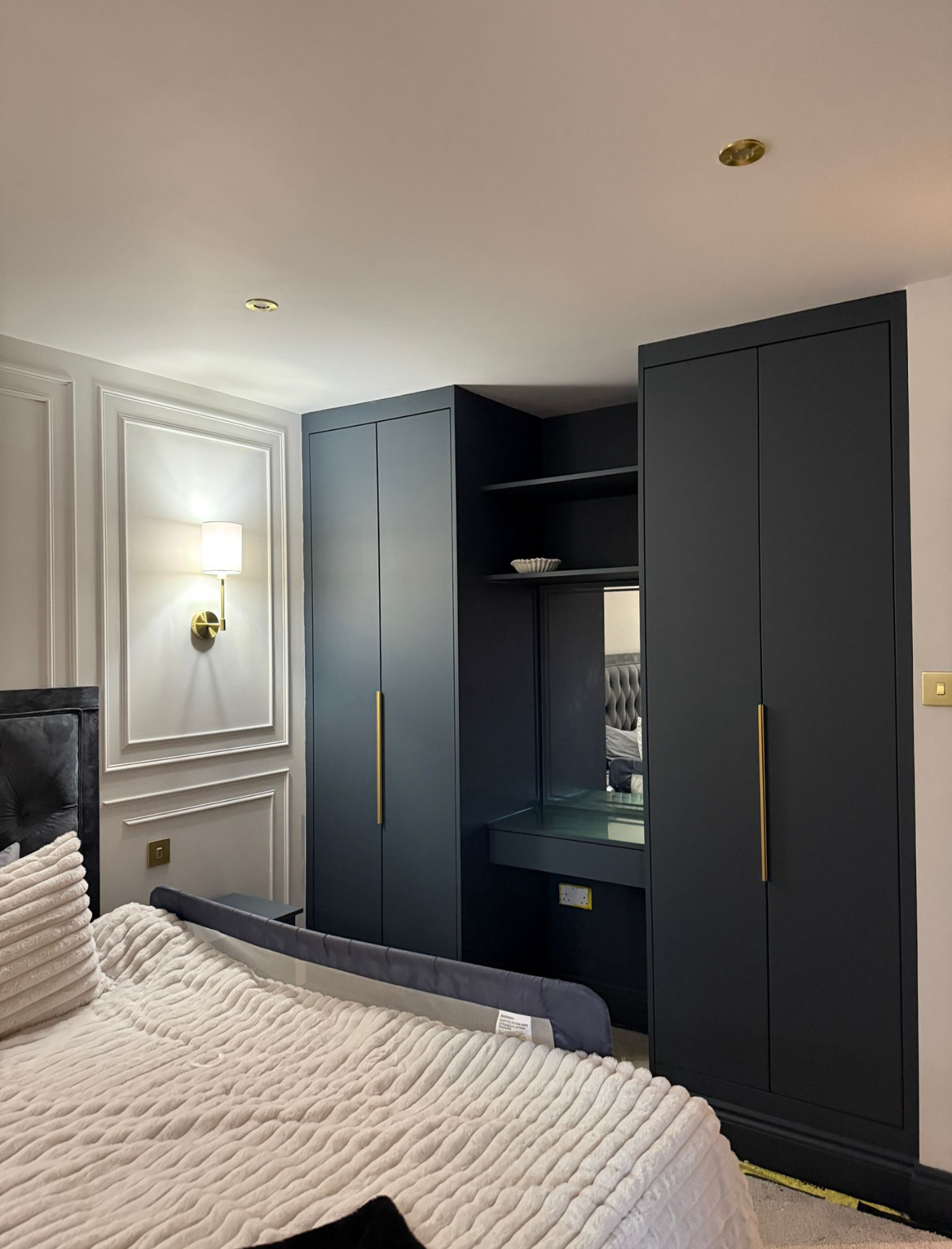 Dark fitted wardrobe with a built-in dressing table, mirror and brass handles