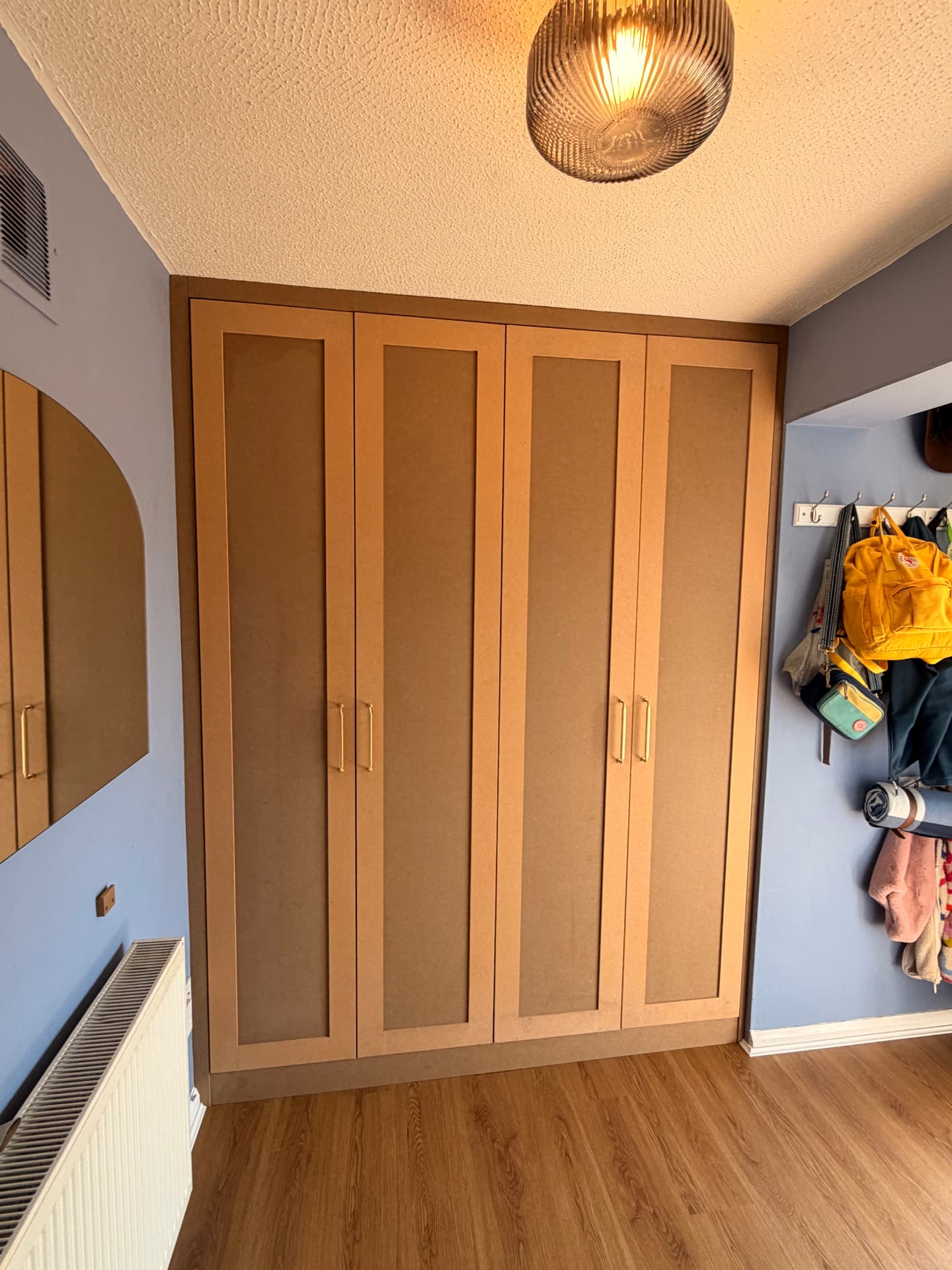 Four-door fitted wardrobe with shaker panels and brass handles in a blue bedroom